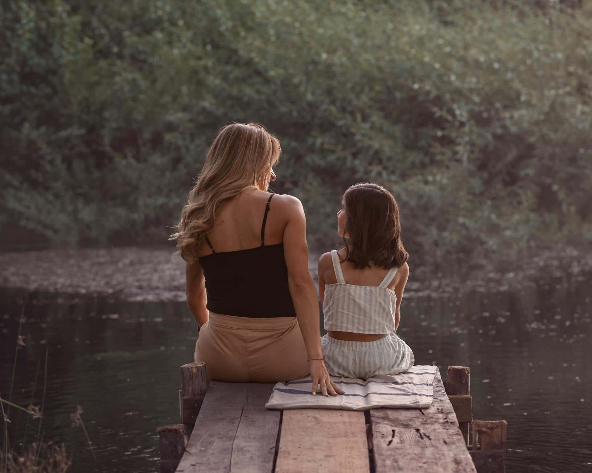 Mother and daughter sitting quietly on a dock by the water, sharing a calm, supportive moment illustrating mindful parenting for kids with ADHD.