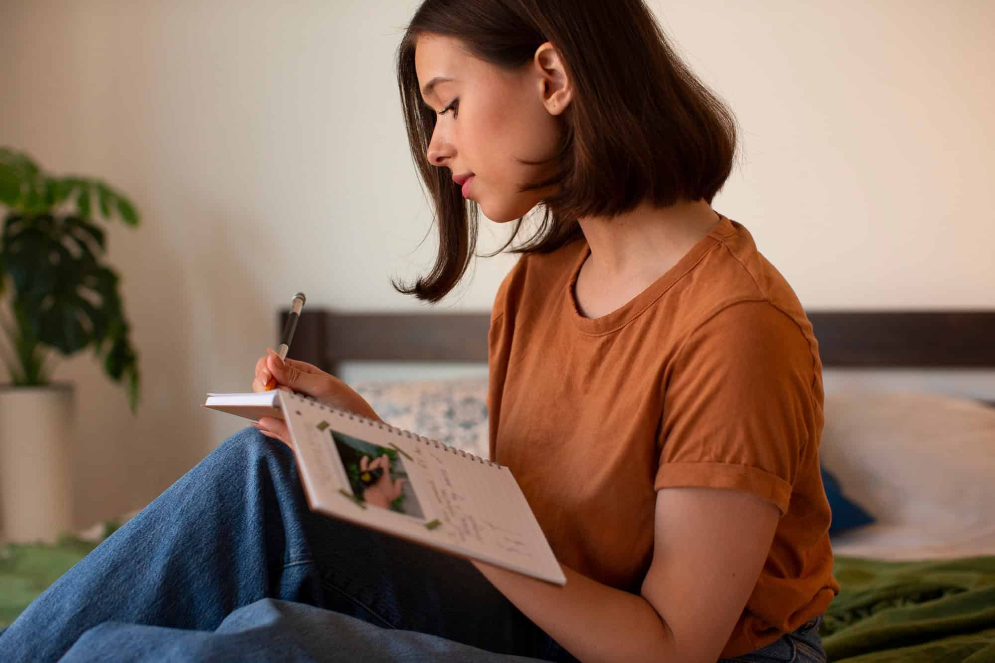 Young woman writing in a notebook at home using journaling as a coping tool to manage ADHD symptoms and improve daily focus.
