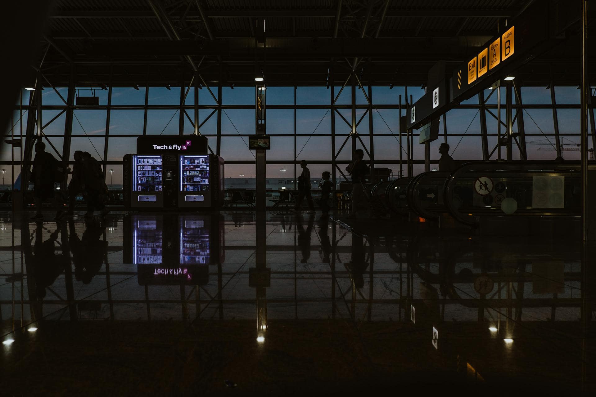 Silhouetted travelers walking through a dimly lit airport terminal at dusk, symbolizing pre-flight anxiety and the tense atmosphere before boarding.