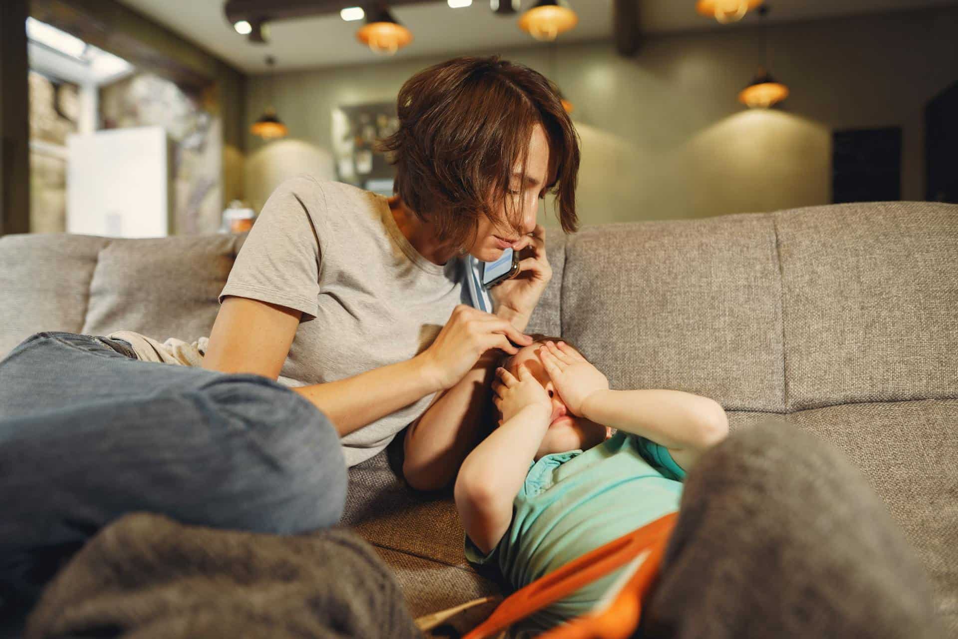 concerned mother comforts her child at home, possibly noticing symptoms of bruxism in kids such as jaw discomfort or sleep disturbances.