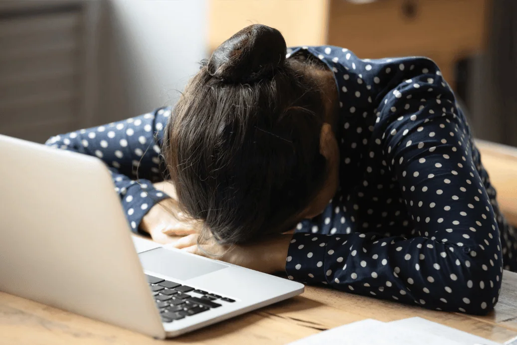 Woman resting her head on a desk at the end of a full on day