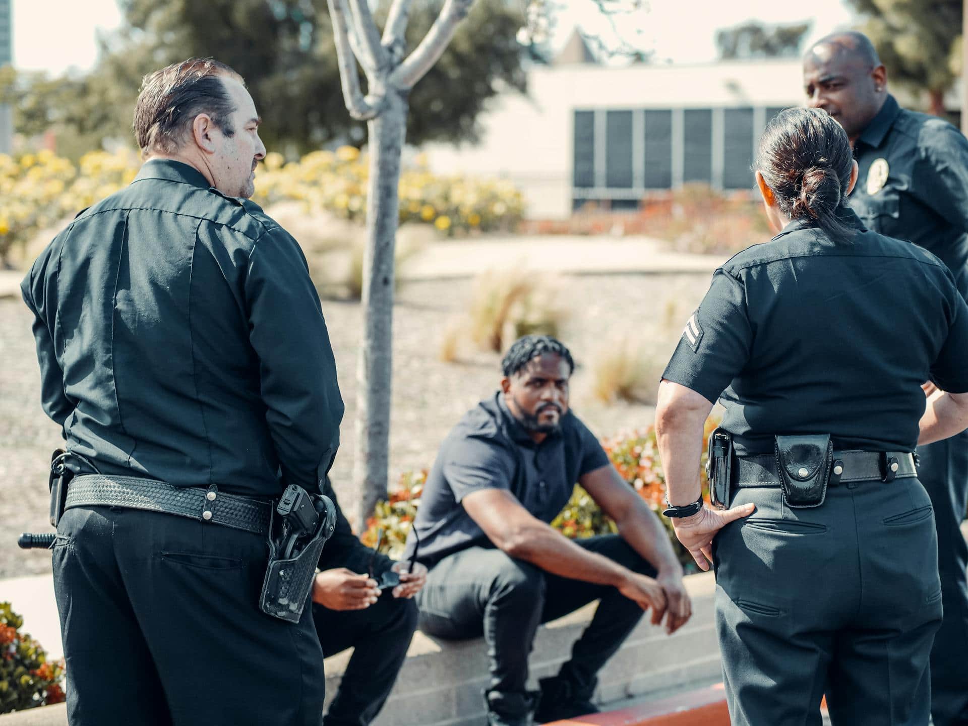 Correctional officers are engaged in conversation with a suspect, maintaining a firm yet controlled demeanor, likely assessing the situation or issuing instructions.
