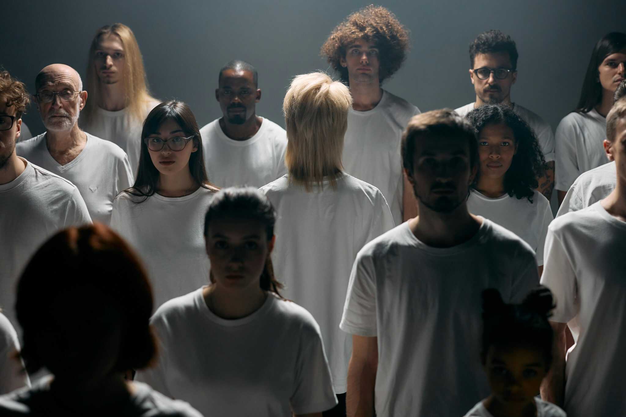 Group of people wearing white shirts with one person turned away, symbolizing disconnection, isolation, and the experience of disassociation