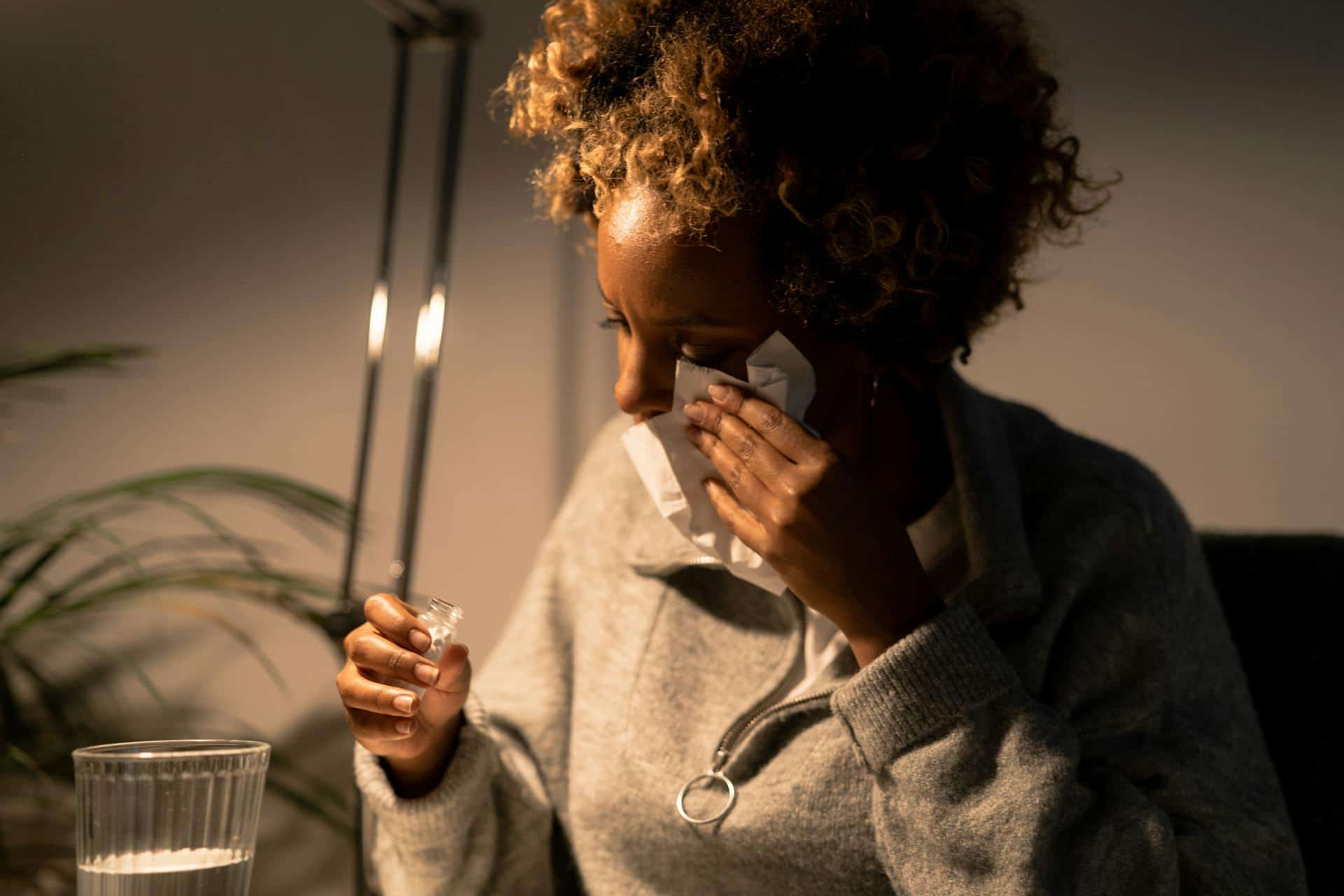 A stressed woman wiping her tears while holding a small vial, symbolizing the emotional toll that can contribute to TMJ pain.