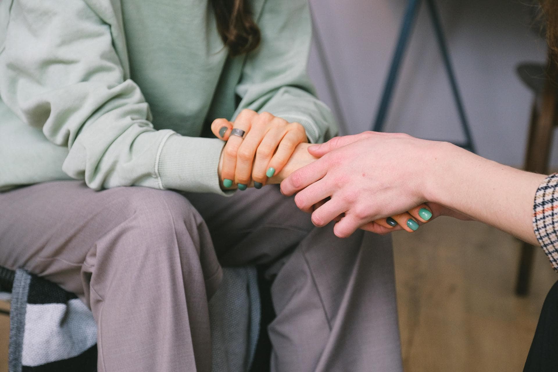 Close-up of two people holding hands in a comforting gesture, symbolizing support and empathy.