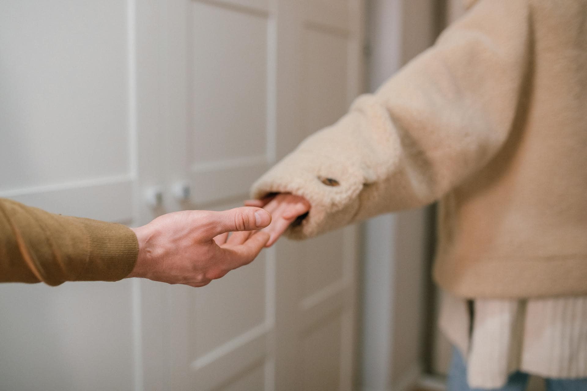 Close-up of two people holding hands, symbolizing emotional support and connection during mental health recovery