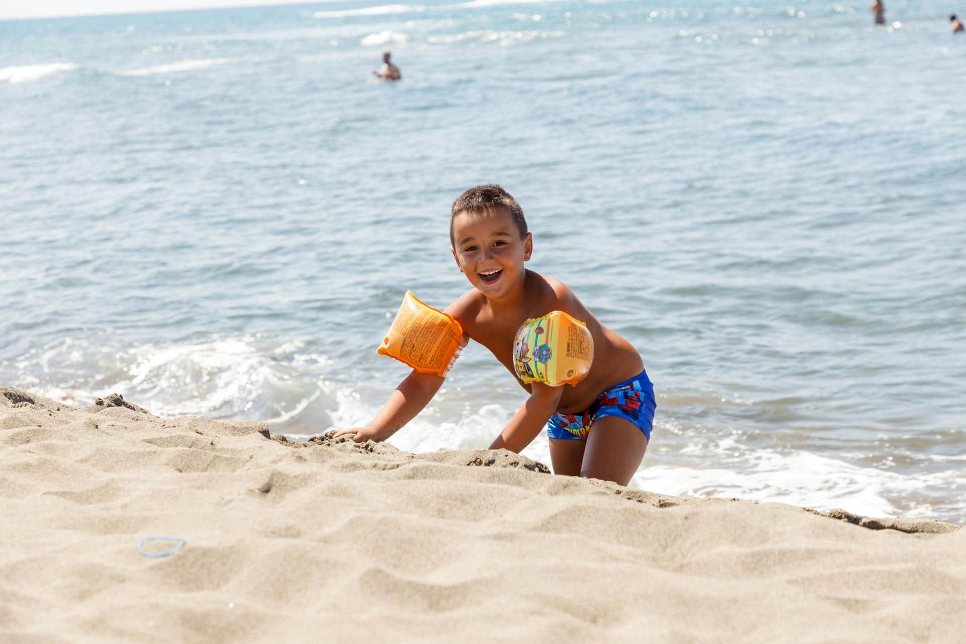 Smiling young boy playing on the beach, representing the difference between natural high energy and ADHD symptoms in children.