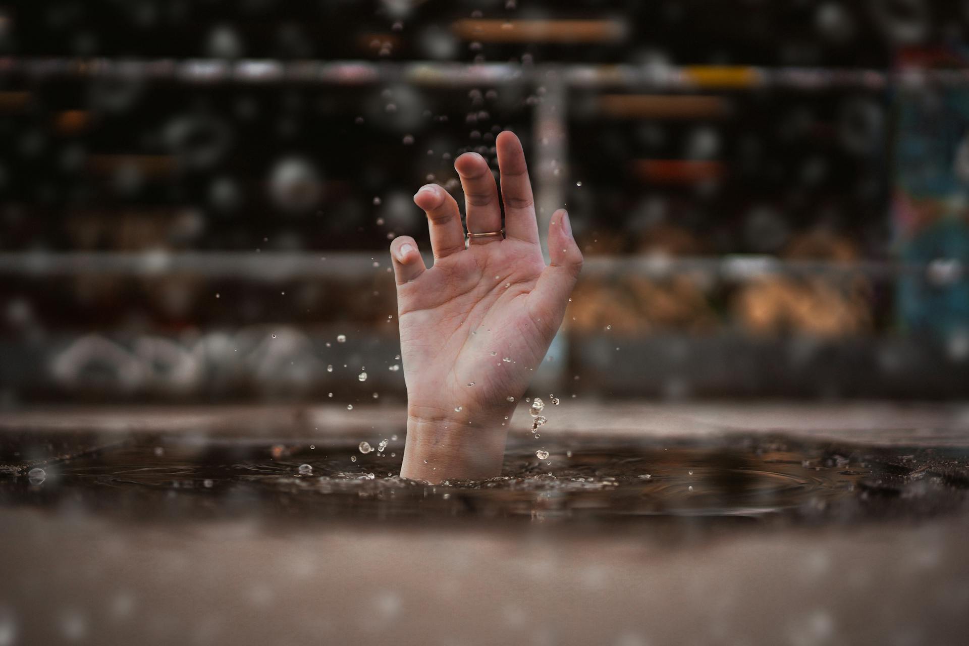 A hand reaching out of water, symbolising emotional overwhelm, stress, or a cry for help during a mental health crisis.