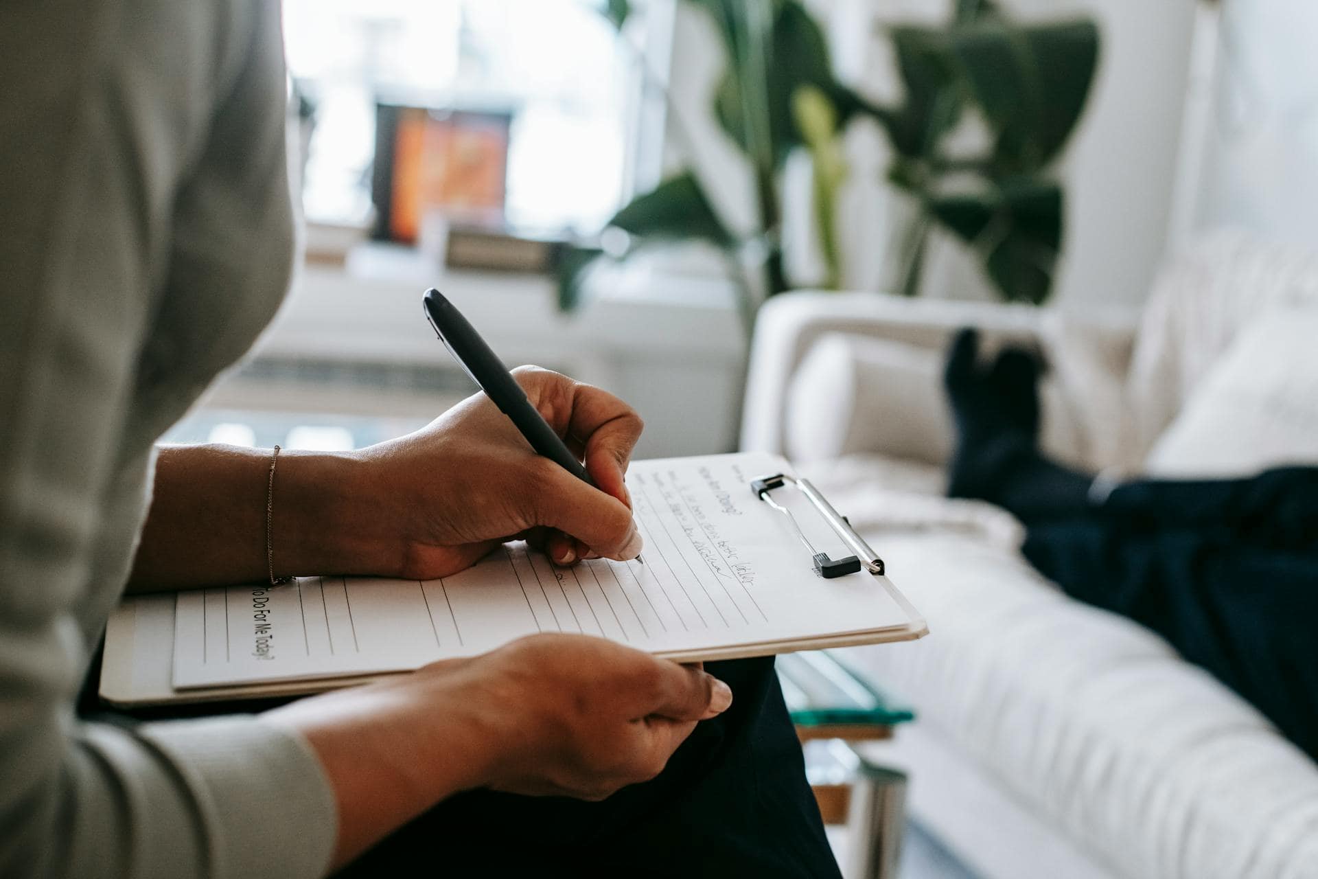 Therapist taking notes during a hypnotherapy session.