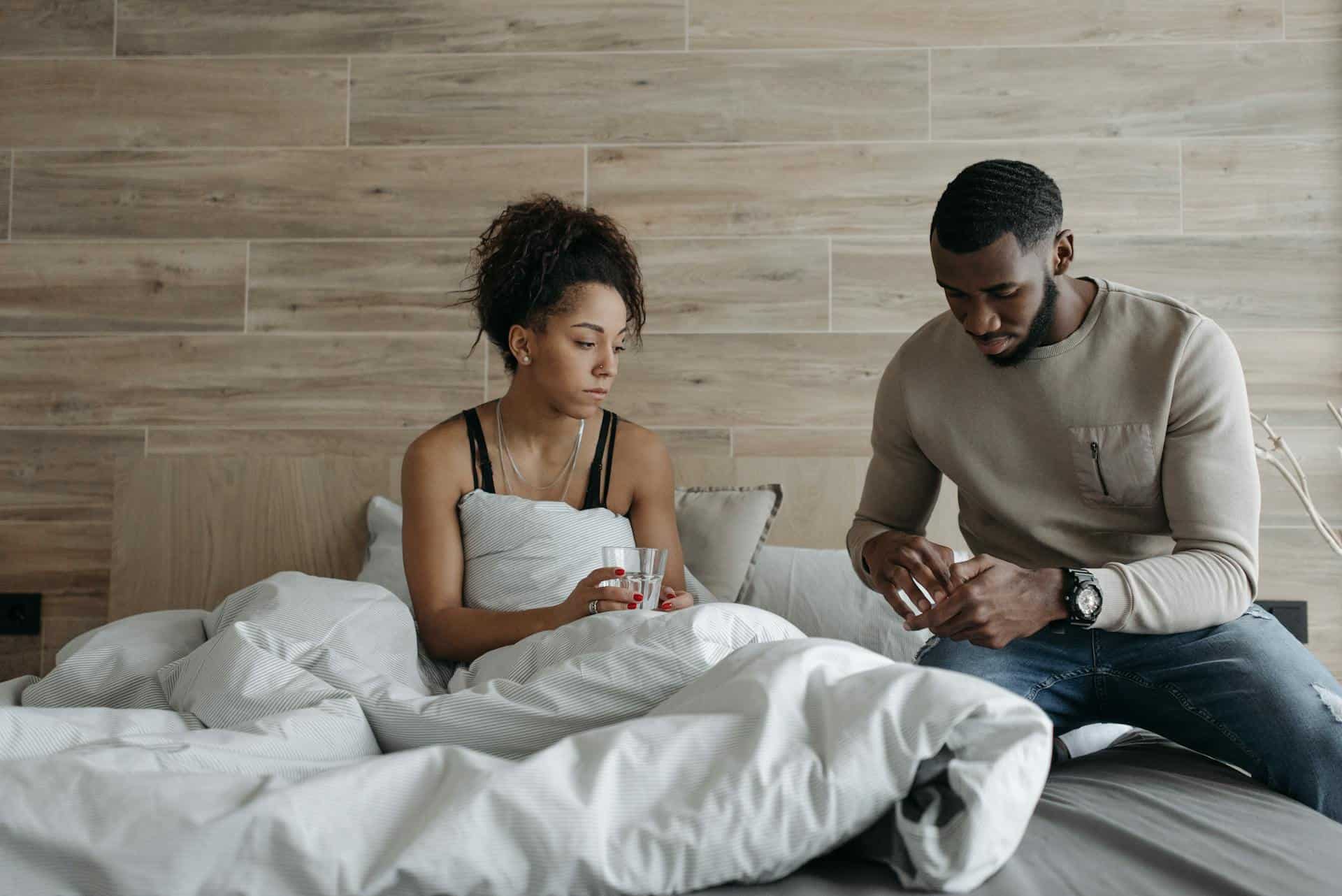 Man helping a woman in bed who appears unwell, offering support possibly for a morning headache