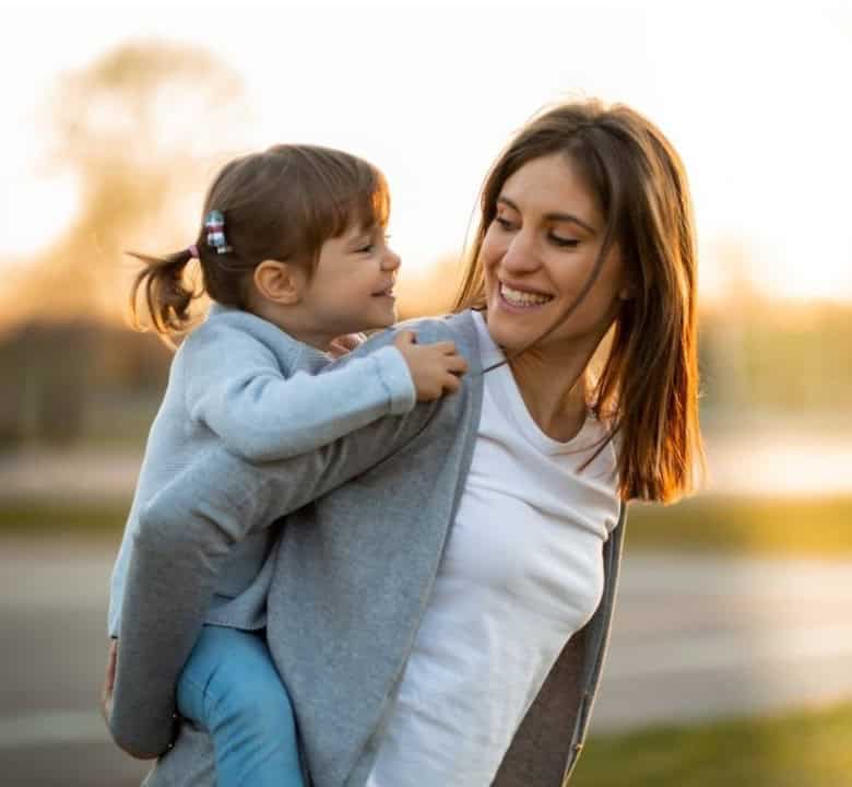Mother lifting her small daughter up, both laughing