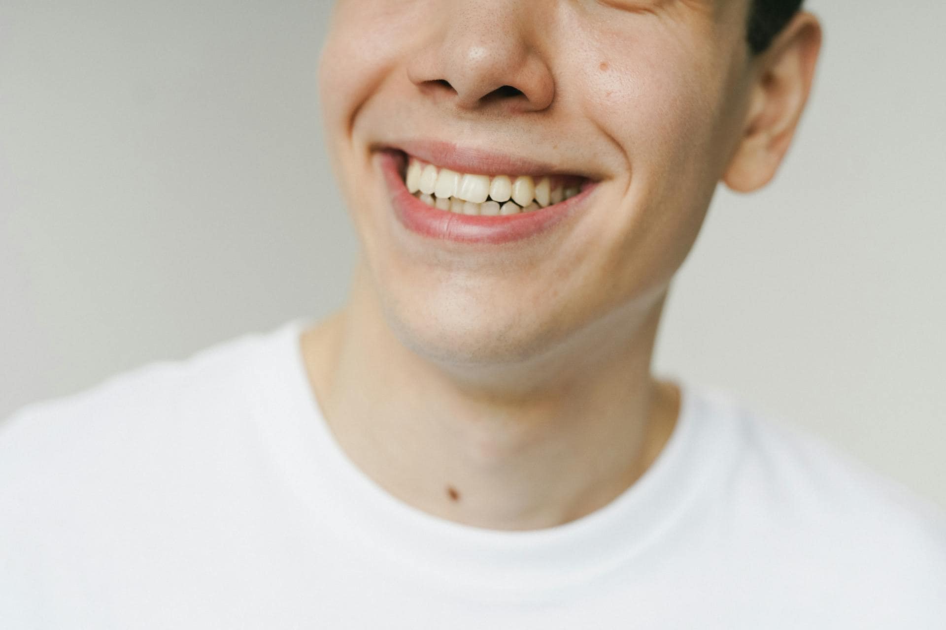 Close-up of a smiling person in a white shirt, symbolizing relief and recovery from TMJ disorder.
