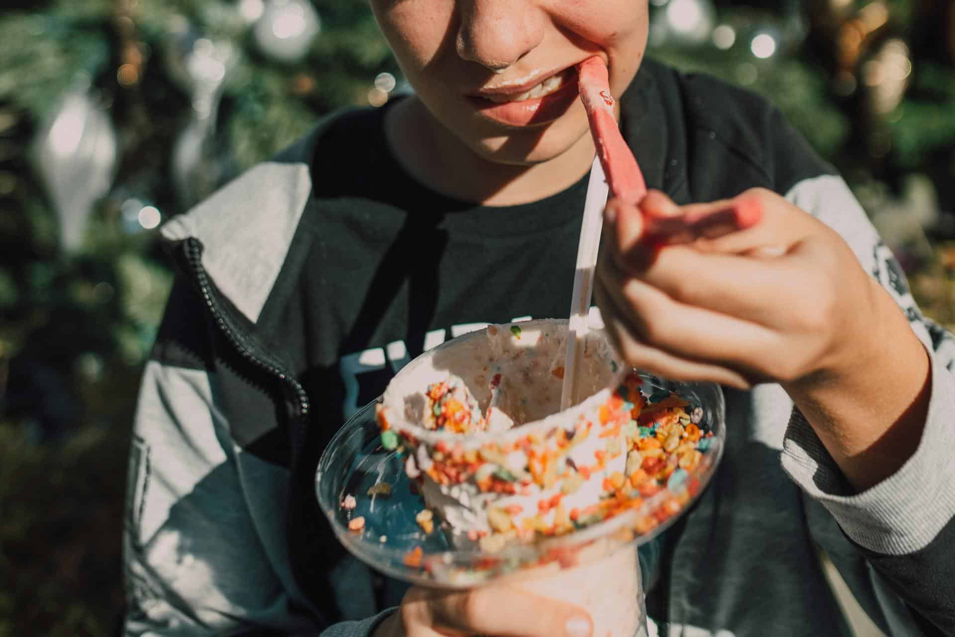 A person eating a colorful dessert with chewy candy, representing foods that may aggravate TMJ disorder symptoms.