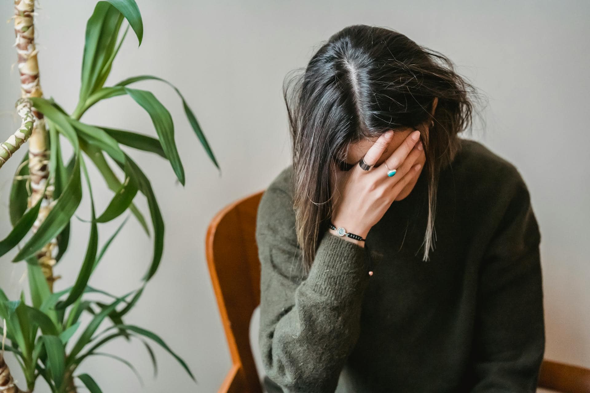 Stressed woman holding her face in her hand, representing burnout and emotional fatigue in women frontline workers