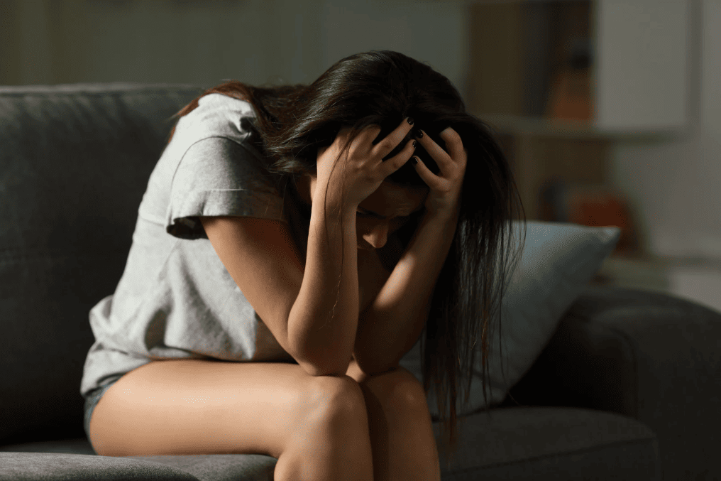 Woman sitting on a couch with her head in her hands