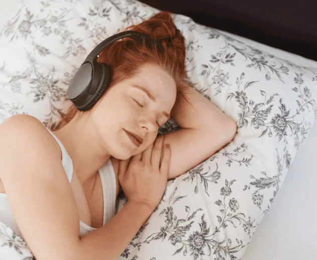 Woman asleep in bed wearing headphones