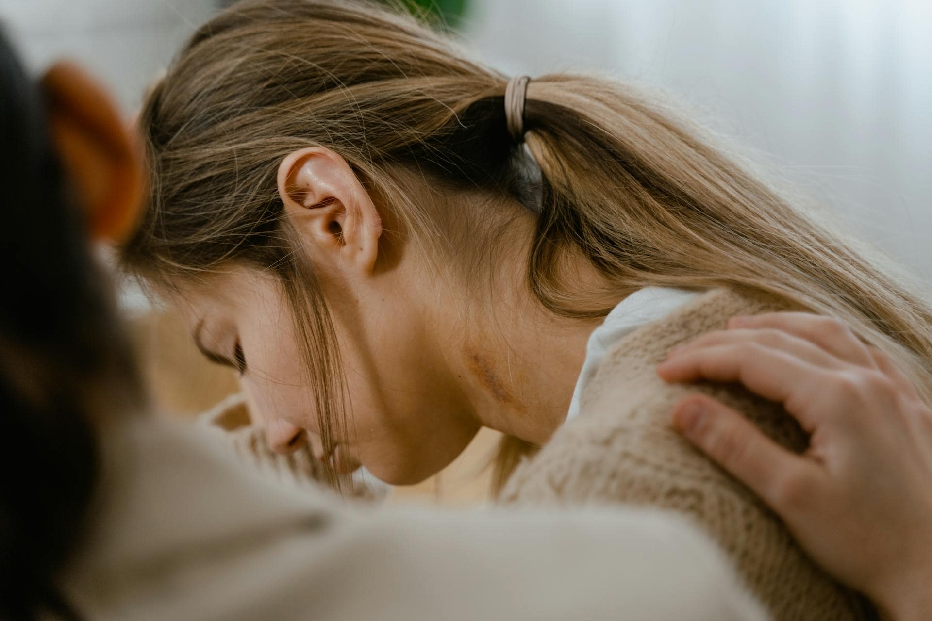 Close-up of a distressed woman receiving support, symbolizing trauma recovery and emotional support for women in emergency services